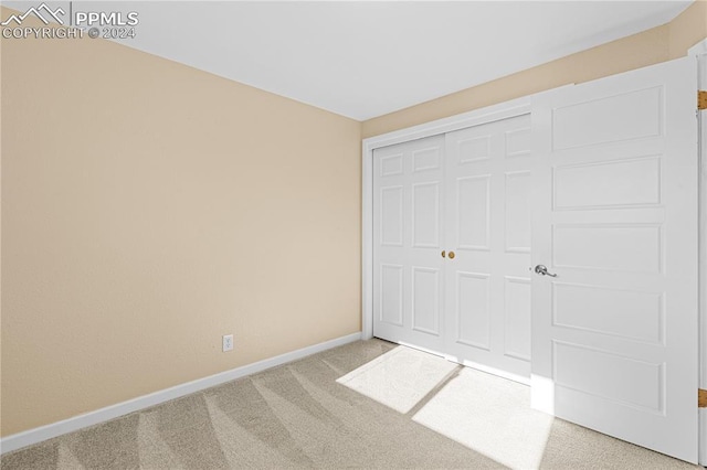 unfurnished bedroom featuring light carpet and a closet