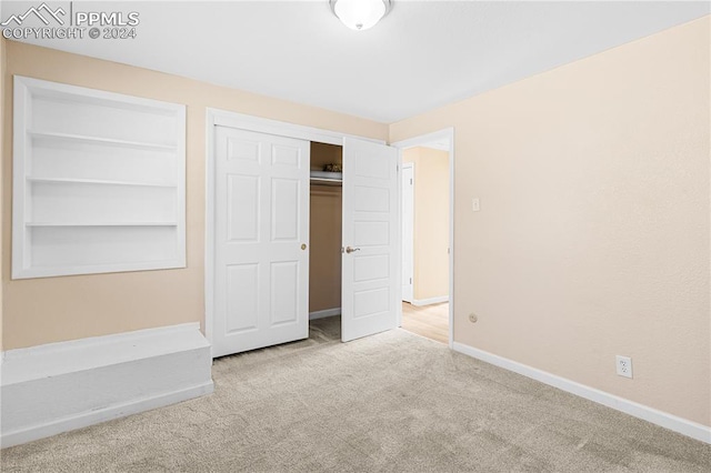 unfurnished bedroom with light carpet and a closet