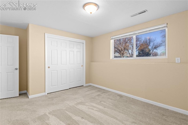 unfurnished bedroom with light carpet and a closet