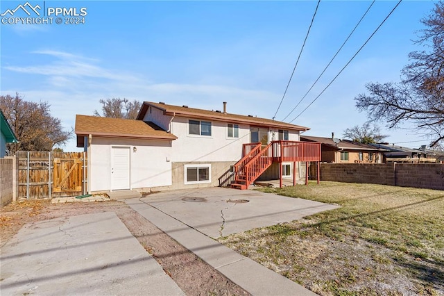 rear view of property featuring a lawn, a patio area, and a deck