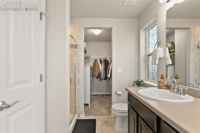 bathroom with tile patterned flooring, vanity, toilet, and walk in shower