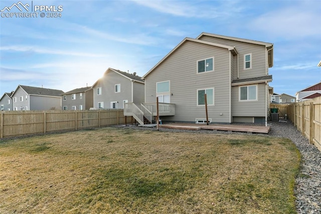 back of property with a deck, central air condition unit, and a lawn