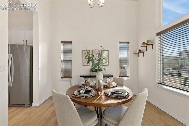 dining room featuring a towering ceiling and light hardwood / wood-style floors