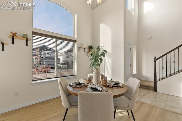 dining room featuring a towering ceiling and light wood-type flooring