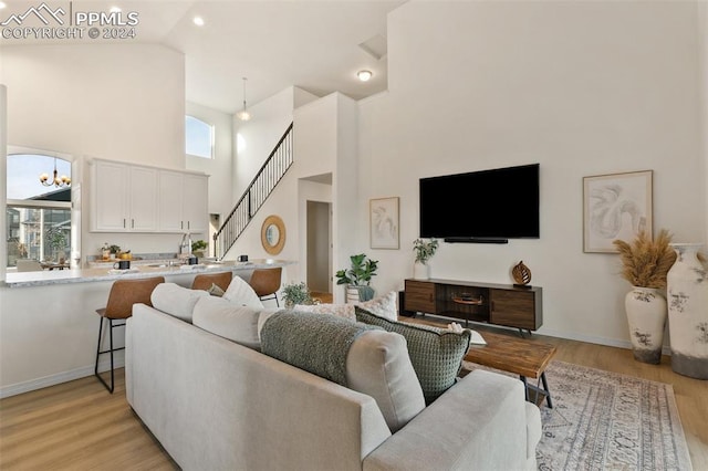 living room with sink, plenty of natural light, light hardwood / wood-style floors, and a chandelier