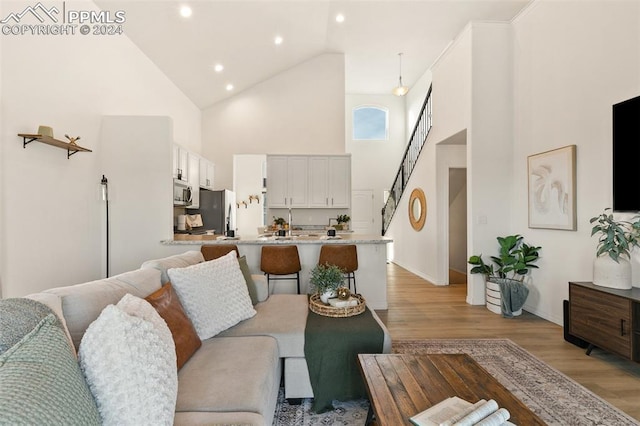 living room featuring high vaulted ceiling and light wood-type flooring