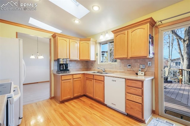 kitchen featuring a skylight, decorative light fixtures, tasteful backsplash, light countertops, and white appliances