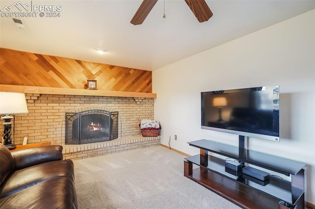 living room featuring wooden walls, carpet flooring, a ceiling fan, baseboards, and a brick fireplace