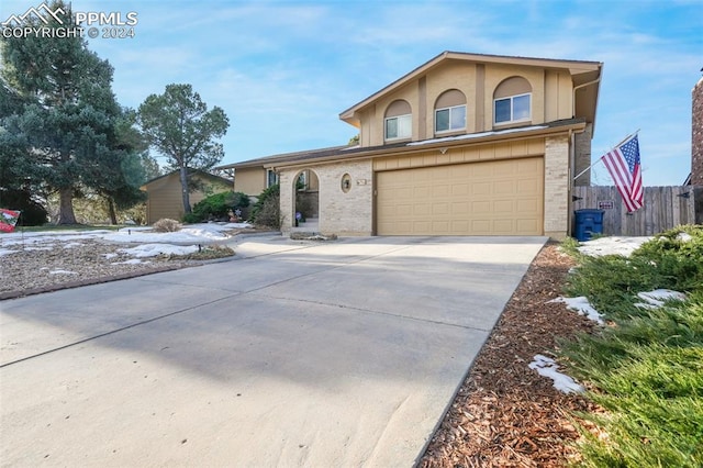 traditional home featuring brick siding, stucco siding, fence, a garage, and driveway