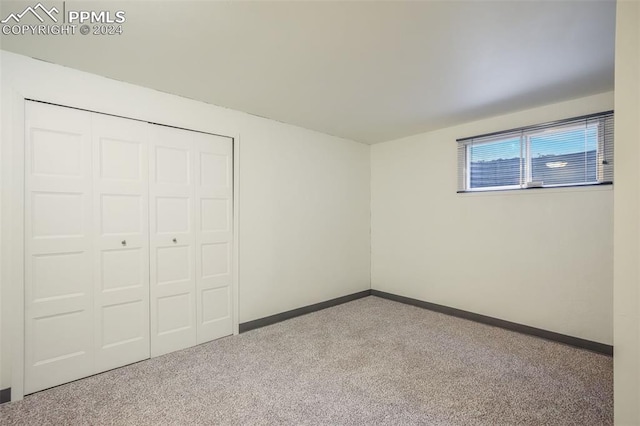 unfurnished bedroom with a closet, light colored carpet, and baseboards