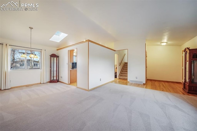 spare room featuring a skylight, light colored carpet, visible vents, baseboards, and stairs