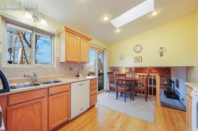 kitchen featuring a sink, lofted ceiling with skylight, light countertops, and dishwasher