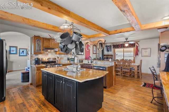 kitchen featuring backsplash, light stone countertops, a kitchen island, kitchen peninsula, and stainless steel appliances