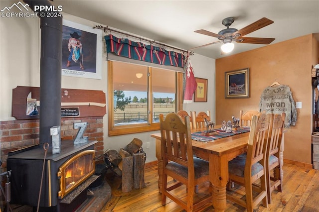 dining area featuring a wood stove, ceiling fan, and light hardwood / wood-style floors