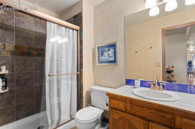 bathroom featuring tiled shower, vanity, and toilet