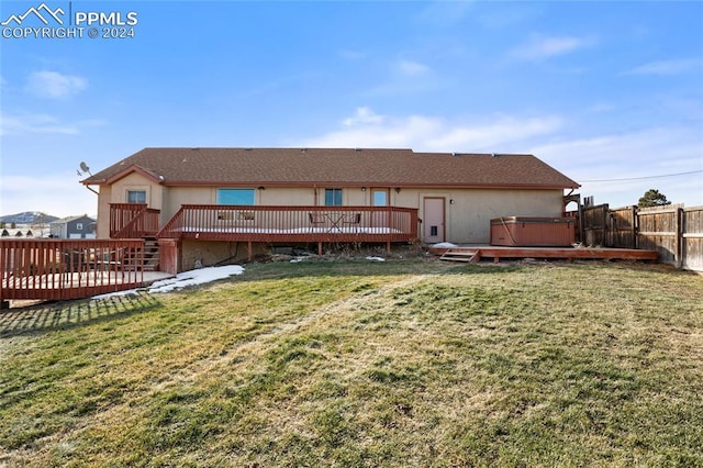 back of property with a lawn, a deck, and a hot tub