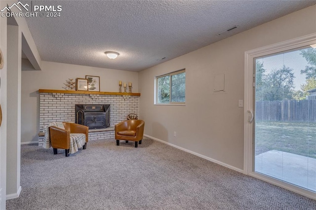 sitting room with a wood stove, a wealth of natural light, carpet, and a textured ceiling