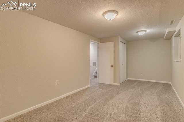 empty room with carpet and a textured ceiling