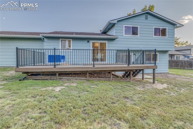 rear view of house featuring a deck and a lawn