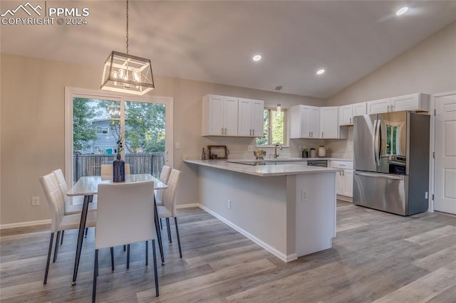 kitchen featuring kitchen peninsula, stainless steel fridge, white cabinetry, and a kitchen breakfast bar