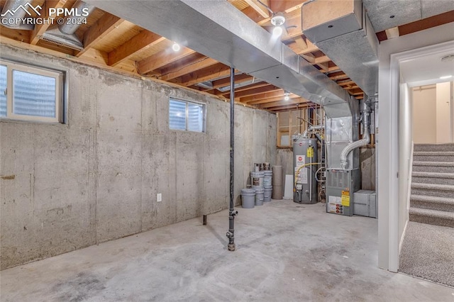 basement featuring heating unit, plenty of natural light, and gas water heater