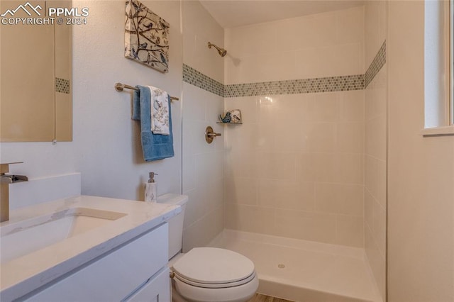 bathroom featuring tiled shower, vanity, and toilet