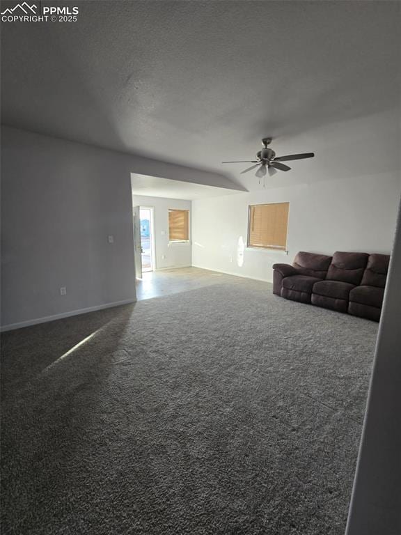 unfurnished living room with ceiling fan and dark colored carpet