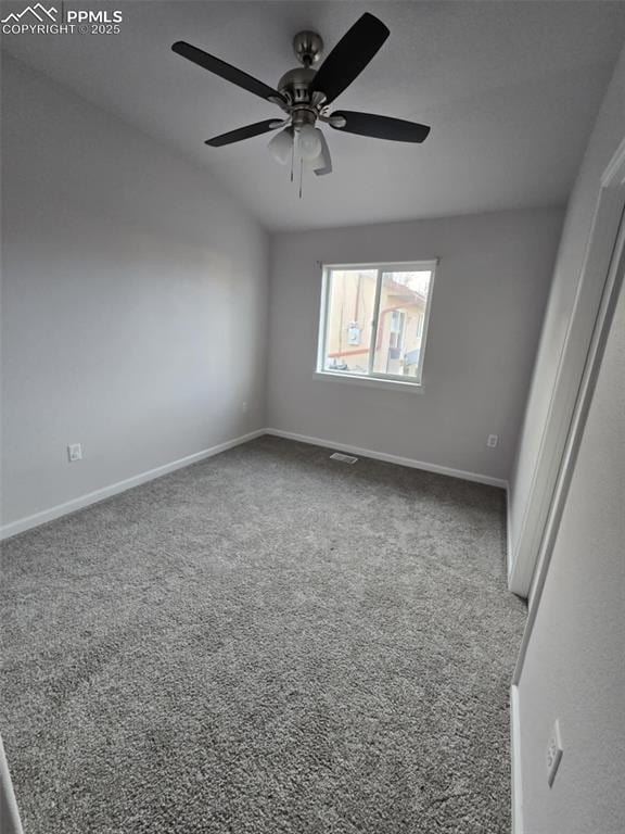 carpeted spare room featuring ceiling fan and vaulted ceiling