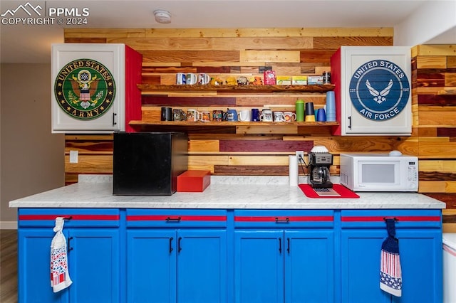 kitchen featuring blue cabinetry and wood walls