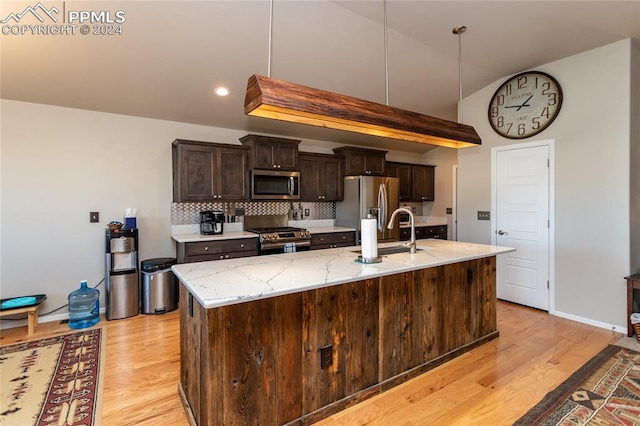 kitchen featuring sink, stainless steel appliances, tasteful backsplash, light hardwood / wood-style flooring, and dark brown cabinets