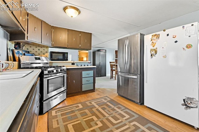 kitchen featuring sink, light hardwood / wood-style flooring, backsplash, dark brown cabinets, and appliances with stainless steel finishes