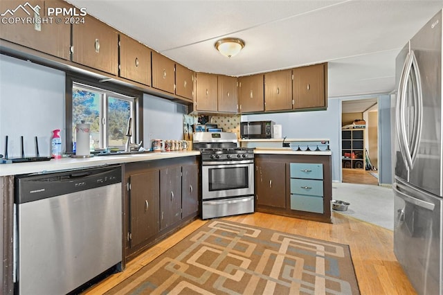 kitchen featuring dark brown cabinets, sink, light wood-type flooring, and stainless steel appliances