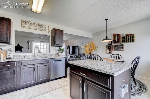 kitchen featuring sink, hanging light fixtures, stainless steel dishwasher, a textured ceiling, and a kitchen island