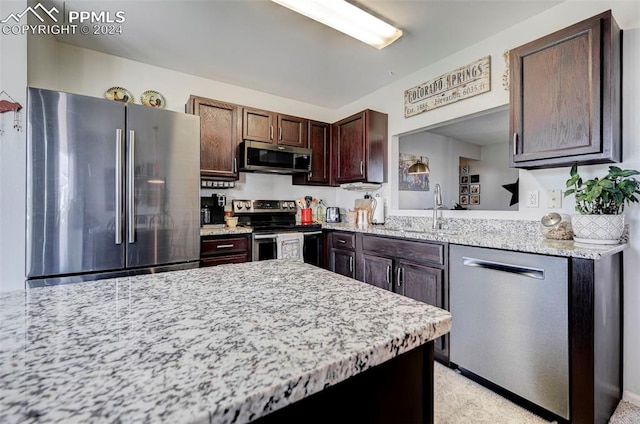 kitchen with light stone counters, sink, stainless steel appliances, and dark brown cabinets