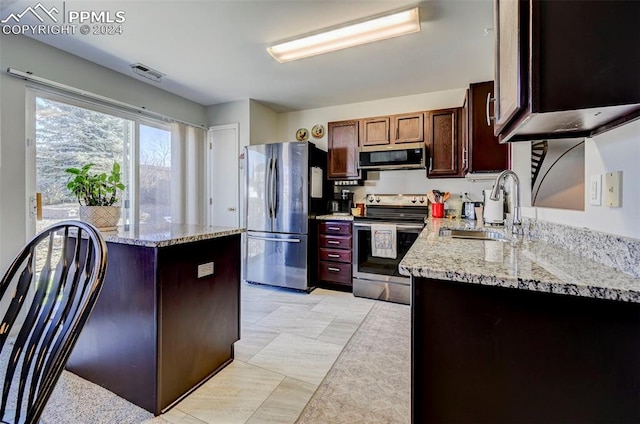 kitchen featuring sink, light stone countertops, stainless steel appliances, and light tile patterned floors