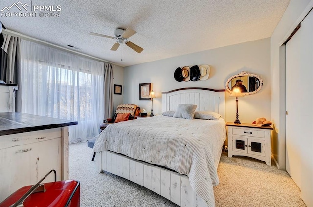 carpeted bedroom with ceiling fan, a closet, and a textured ceiling