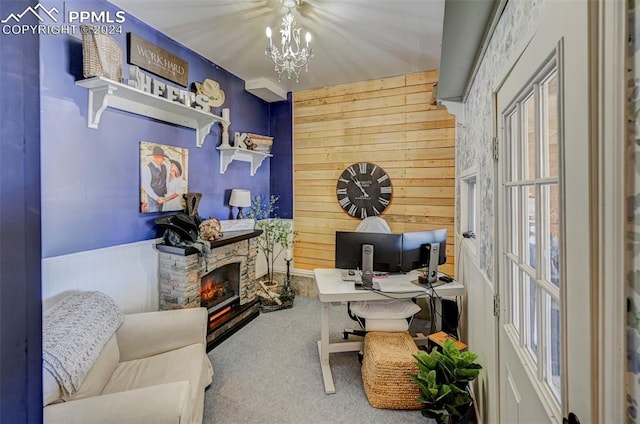 carpeted office space featuring an inviting chandelier, a stone fireplace, and wood walls