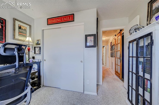 carpeted home office featuring a textured ceiling