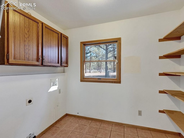 washroom with electric dryer hookup, hookup for a washing machine, light tile patterned flooring, and cabinets