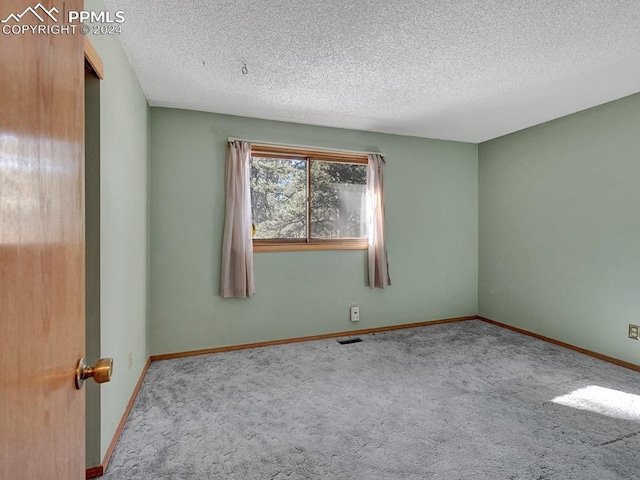 carpeted empty room featuring a textured ceiling