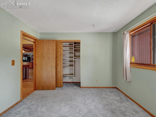 unfurnished bedroom featuring a closet, light colored carpet, and a textured ceiling