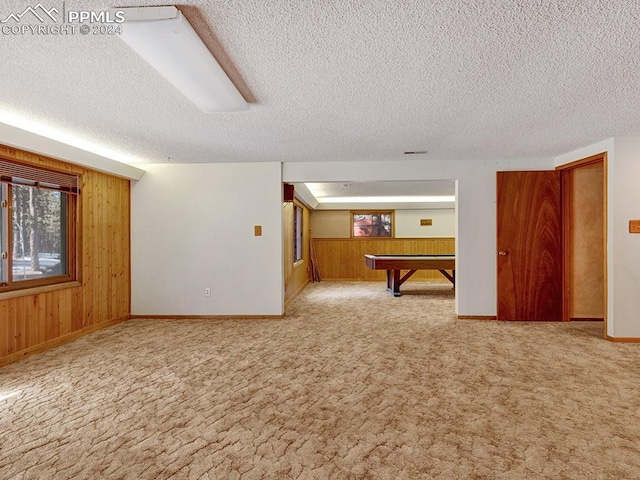 interior space with wood walls, light colored carpet, a textured ceiling, and billiards