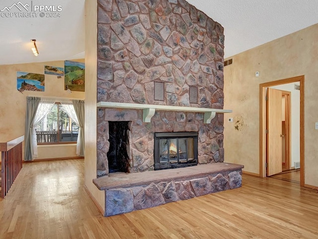 living room featuring a stone fireplace, lofted ceiling, and hardwood / wood-style flooring