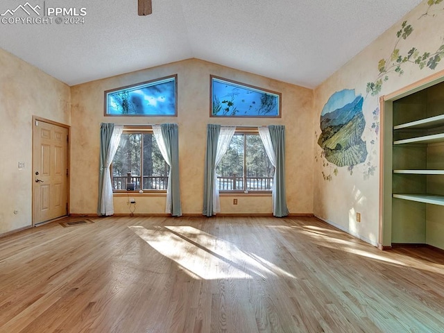 interior space featuring hardwood / wood-style floors, built in features, a textured ceiling, and vaulted ceiling