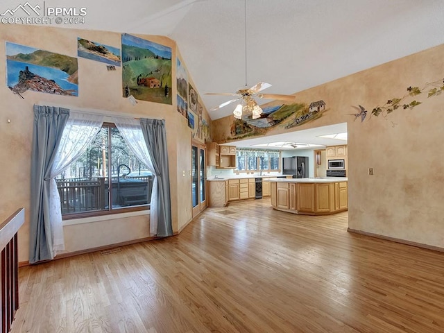 kitchen with stainless steel microwave, a center island, light brown cabinets, black fridge, and light hardwood / wood-style floors