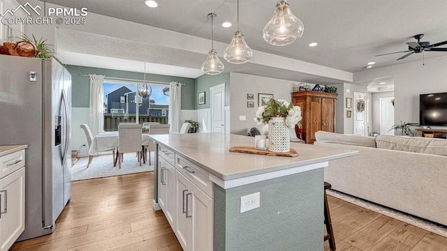 kitchen with a center island, stainless steel fridge, white cabinetry, and pendant lighting