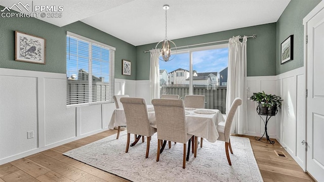 dining space with light hardwood / wood-style flooring and a notable chandelier