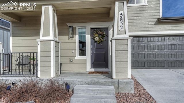 view of exterior entry featuring a porch and a garage