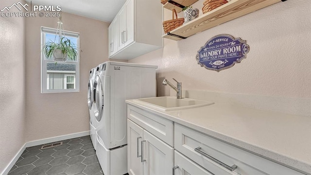 laundry area featuring washer and dryer, cabinets, dark tile patterned floors, and sink