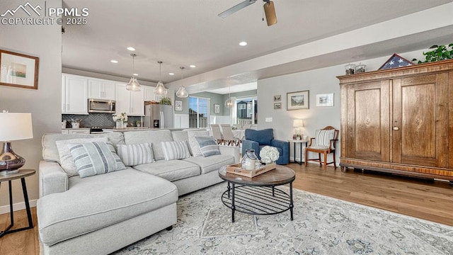 living room with ceiling fan and light wood-type flooring